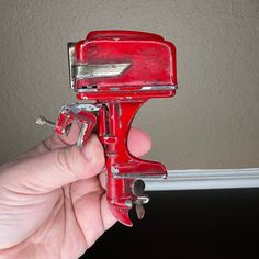 a hand holding a red paint roller with two screwdrivers attached to the handle