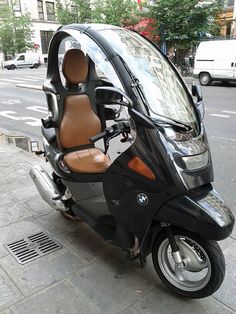 a small black motorcycle parked next to a street