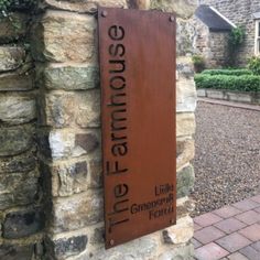 a sign that is on the side of a stone wall in front of a house