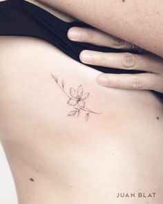 a woman's stomach with a small flower tattoo on her left side ribcage