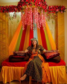 a woman sitting on top of a bed in front of a canopy covered with flowers