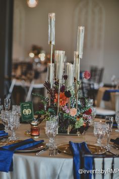 the table is set with silverware, candles and flower arrangements on it's centerpieces