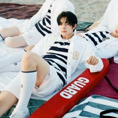 two young men laying on the beach next to each other