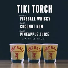 three shot glasses sitting next to each other on top of a wooden table with the words tiki torch