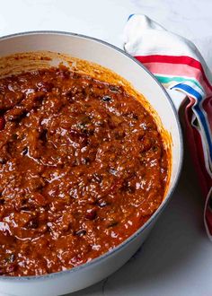 a white bowl filled with chili next to a red and blue striped napkin on top of a table