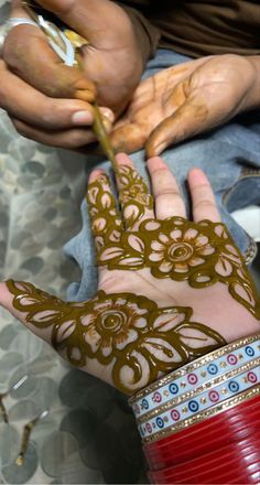 a person with henna on their hand holding something in the other hand and wearing bracelets