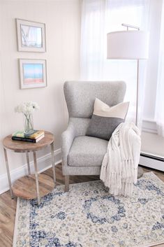 a living room with a chair, rug and lamp on the side table in front of a window