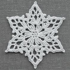 a white snowflake is shown on a gray background with the words, crochet christmas ornament