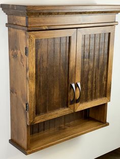 a wooden cabinet with two doors on the front and one door open to reveal a toilet paper dispenser