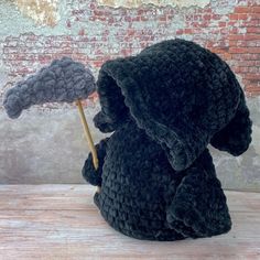 a stuffed animal holding an umbrella on top of a wooden table in front of a brick wall