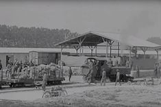 an old black and white photo of people loading cargo onto train cars