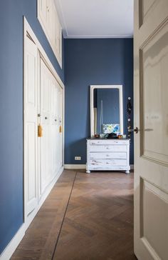 an empty hallway with blue walls and white furniture