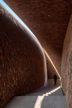 a person walking up some stairs in a brick building with sunlight coming through the windows