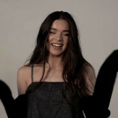 a woman with long hair is smiling and waving her arms