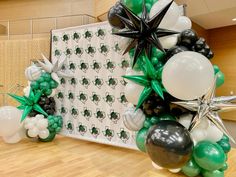 an arrangement of balloons and streamers are displayed on the floor in front of a wall