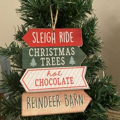 a christmas tree with wooden signs hanging from it's branches and the words sleigh ride, christmas trees not chocolate, reindeer barn