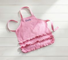 a child's pink gingham apron with personalized name on the front