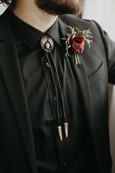 a man wearing a black suit and red flower boutonniere