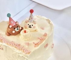 there is a cake with two bears on it and one has a candle in the shape of a heart