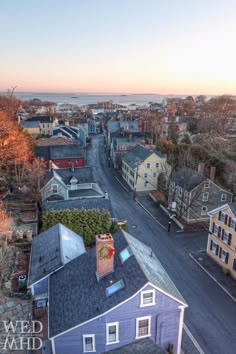 an aerial view of a neighborhood with houses and the ocean in the background at sunset