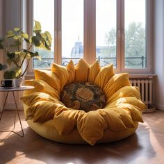 a large yellow bean bag chair sitting in front of two windows on a hard wood floor