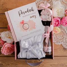 an open box containing perfume and flowers on a wooden table next to a lace doily