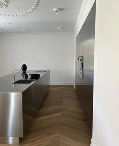 an empty kitchen with stainless steel appliances and wood flooring