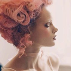 a woman with pink hair is looking off into the distance