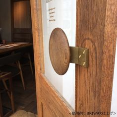 an open door with a wooden handle on the glass and wood frame around it, in front of a dining room table