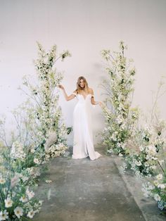 a woman in a white dress standing between flowers