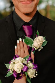 a close up of a person wearing a suit and tie with flowers on his lapel