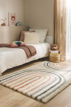 a bedroom with a bed, rug and teddy bear on the floor in front of it