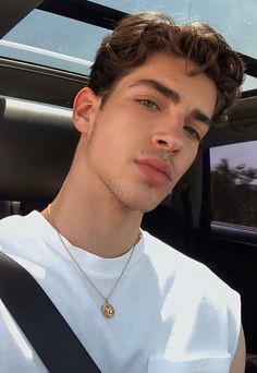 a young man sitting in the back seat of a car wearing a white t - shirt