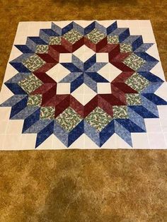 a blue, red and white quilt on the floor