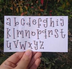 a hand holding up a piece of paper with letters on it