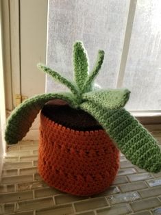 a crocheted pot with a green leaf on it sitting in front of a window