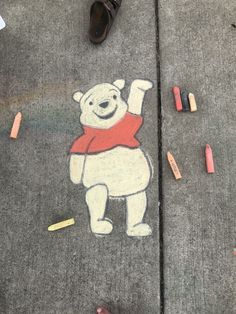 someone's feet are standing on the sidewalk with chalk crayons