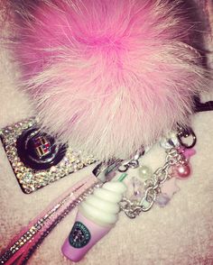 a pink furry ball, keychain, and other items are laying on the floor