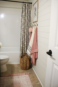 a bathroom with towels hanging on the wall and a basket in front of the tub