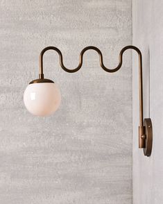 a white ball hanging from the side of a light fixture on a concrete wall next to a lamp