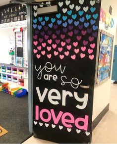 a very colorful door with hearts painted on it in a school hallway that says you are very loved