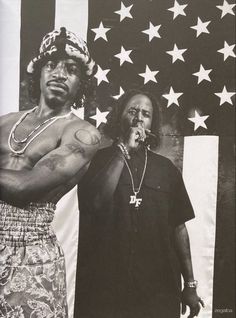 two men standing in front of an american flag