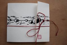 a piece of paper with red string tied to it on top of a wooden table