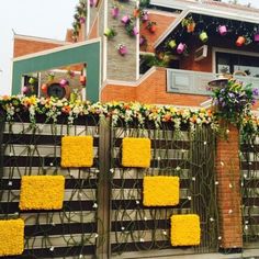 yellow flowers are growing on the top of a brick building with a wooden fence in front of it