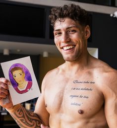 a shirtless man holding up a card with a drawing on it