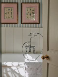 a bath tub sitting under two framed pictures