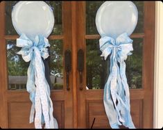 two balloons are tied to the front door with blue ribbons and bows on each balloon