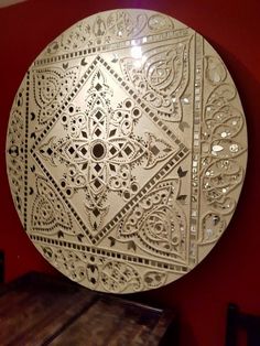 a decorative white plate sitting on top of a wooden table next to a red wall