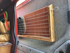 a guitar hanging from the side of a car with other items in it's back compartment