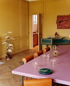 a dining room with yellow walls and purple table cloths on the top of it